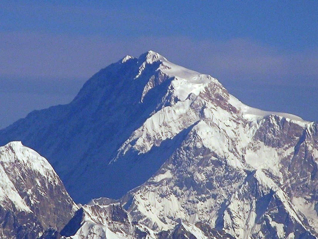 Kathmandu Mountain Flight 03-3 Shishapangma Close Up Here is a close-up of the summit area of Shishapangma, the 14th highest mountain in the world at 8012m, shining in the early morning sun from Kathmandu Mountain flight. The steep and treacherous southwest face is in shadow on the left. The north face is just visible in the sun on the right. The peak to the right of the sloping long sunny ridge in the middle right is Pungpa Ri (7445m), first climbed in 1982. On the far left below Pungpa Ri with its west face in shadow and the east face fully lit is Nyanang Ri (7071m), called the Rock Tooth.